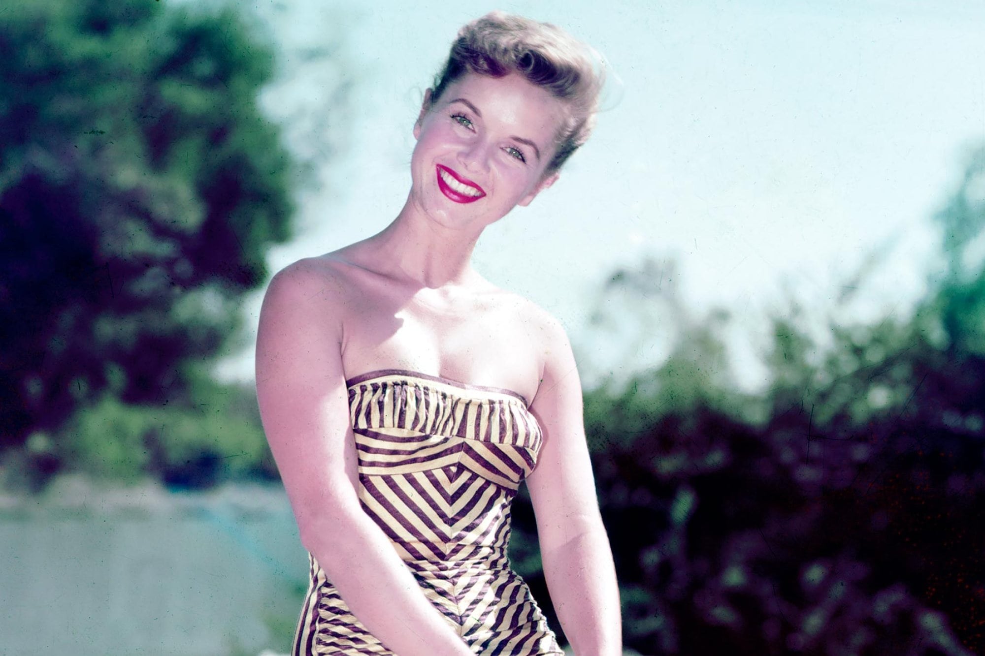 Debbie Reynolds, US actress, singer and dancer, smiling while wearing a swimsuit, sitting beside a swimming pool, circa 1955. (Photo by Silver Screen Collection/Getty Images)